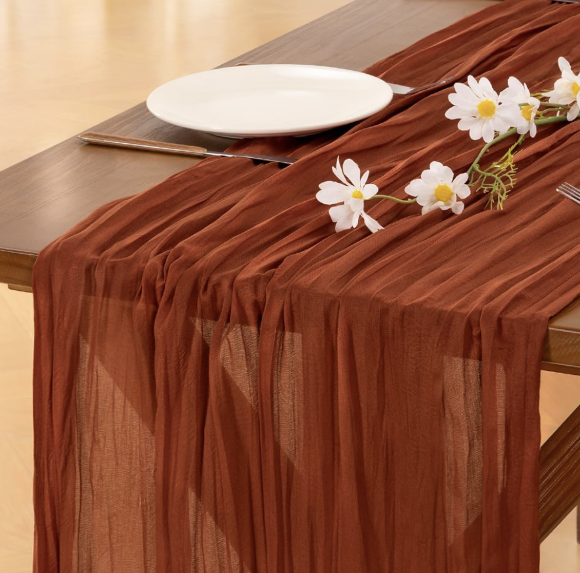 Table runner de cheesecloth color terracota sobre una mesa decorada